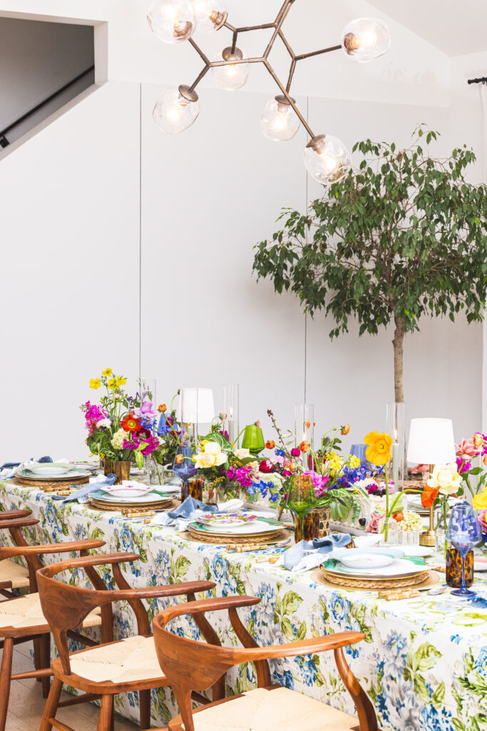 A bountiful table set with pattern filled textiles, place settings, and florals. 